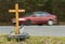 A roadside memorial cross with a candles commemorating the tragic death