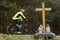 A roadside memorial cross with a candles commemorating the tragic death, on a background ride blurred cyclist