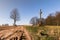 A roadside wooden cross. A dirt road to the village.