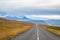 Roadtrip in Iceland empty paved road leading over mountains with snow covered tips next to power line