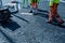 Roadworker applying thermoplastic road marking on the freshly laid tarmac during new roundabout and access road construction