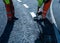 Roadworker applying thermoplastic road marking on the freshly laid tarmac during new roundabout and access road construction