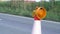 Roadworks cone flashing on UK motorway at evening with traffic passing