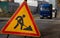 Roadworks warning sign ahead on street sidewalk. Close-up