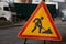 Roadworks warning sign ahead on street sidewalk. Close-up