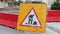 Roadworks yellow sign with red and white barriers. Road under construction. Street blocked for reconstruction. Road detour.