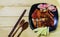 Roast duck and vegetables in black plate and wooden fork,spoon with sauce on wooden background