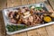 Roast pork knuckle eisbein meat on a baking pan with herbs. Wooden background. Top view