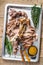 Roast pork knuckle eisbein meat on a baking pan with herbs. Wooden background. Top view