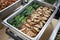 Roast Pork with Vegetables, food in buffet line. The container is a rectangular stainless steel tray.