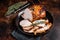 Roast rolled pork ham meat on plate with thyme. Dark background. Top view