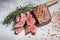 Roast sliced Flank or Flap Steak on a butcher cleaver with thyme and pink salt. Gray background. Top view