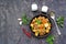 Roast, stewed beef with potatoes and carrots in a brown clay bowl on a dark concrete background