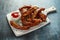 Roasted barbecue hot pork ribs with ketchup on white wooden board