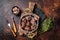 Roasted beef kidney, offal meat in skillet with herbs. Dark background. Top view