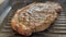 Roasted beef steak frying on a grill pan with smoke and oil splashing. Close up