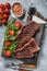 Roasted cap rump or Top sirloin beef meat steak on wooden board with salad. Gray background. Top view