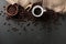 Roasted coffee beans in a cup and wooden spoon on a black background. Robusta, Arabica. top view