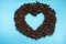 Roasted coffee beans with heart open space in the middle on blue background. Aroma drink concept.