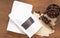 Roasted coffee beans in white transparent window paper bag with zipper and wooden scoop, bowl, filter on rustic wood background.