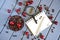 Roasted coffee grains next to red cherries, a notebook, a fountain pen, and a magnifying glass on a light background. Summer