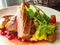 Roasted duck breast with vegetable garnish. The meat is sliced into portions and sprinkled with cranberry berry sauce