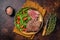 Roasted Flank or Flap Steak in a plate with salad. Dark background. Top view