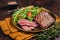 Roasted Flank or Flap Steak in a plate with salad. Dark background. Top view