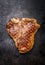 Roasted or grilled T-bone steak on on dark rust metal background, top view