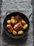 Roasted harissa chicken and new potatoes in a cast iron skillet on a dark background