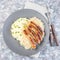 Roasted nuremberg sausages served with sour cabbage and mashed potatoes, on a gray plate, top view, square