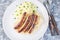 Roasted nuremberg sausages served with sour cabbage and mashed potatoes, horizontal,  top view