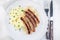 Roasted nuremberg sausages served with sour cabbage and mashed potatoes, on white plate, horizontal, top view