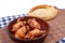 Roasted pigeon in clay pot and loaf of white bread lie on rustic table