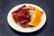 Roasted piglet with orange on white plate on black background