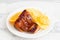 Roasted piglet with potato chips and orange on white plate