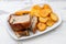 Roasted piglet with potato chips and orange on white plate