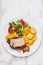 Roasted piglet with potato chips and orange on white plate