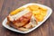 Roasted piglet with potato chips and orange on white plate