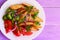 Roasted potato slices, cooked broccoli, fresh tomatoes with spices, red onion, parsley leaves on a white plate