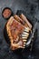 Roasted Rack of lamb ribs, mutton spareribs, sliced meat on plate. Black background. Top view