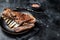 Roasted Rack of lamb ribs, mutton spareribs, sliced meat on plate. Black background. Top view. Copy space