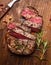 Roasted ribeye steak sliced â€‹â€‹on a cutting board with a fork ,rosemary and peppers, top view, close up