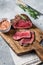 Roasted Rump beef steak sliced on a wooden cutting board. Gray background. Top view