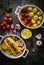 Roasted salmon steak with roast potatoes and tomatoes served in ceramic pan on wooden table