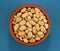 Roasted salted peanuts in bowl on blue background, top view