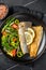 Roasted sea bass fillet with salad, Branzino fish. Black background. Top view