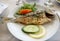 Roasted sea fish on a white plate in greek restaurant.