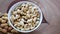 Roasted, skinless peanuts falling into a small jar. Wooden background, side tracking.