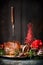Roasted sliced Christmas ham with fork and red festive holiday decoration at dark wooden background